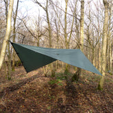DD Tarp 3.5 x 3.5 set up between trees in a forest, showcasing versatility for camping and outdoor adventures.